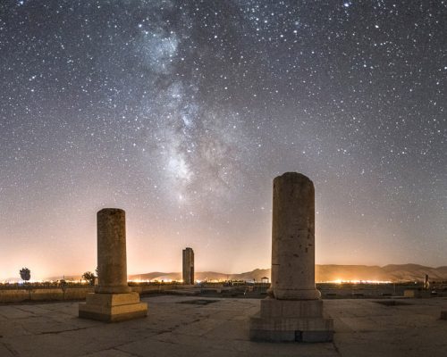 Pasargadae, the capital of Achaemenid Empire under Cyrus the Great, is located in 130 km distance from Shiraz city on its northeast. 
Cyrus the Great issued its construction (529–550 BC) after his victory over Astyages the last king of the Median Empire. 
This complex is well known for its most famous monument, the tomb of Cyrus, but it also includes the prison of Solomon, Pasargadae Palace and citadel.

Royal palace of Cyrus with an area of 3427 km2 is one of the largest palaces of Pasargadae. The creeks in the surroundings of this palace indicate the existence of Persian gardens in this area. 
In the photograph we see the remnants of the Audience Hall of the palace with 30 white columns. Plenty of black and white stones were used in this buildings structure.
 
When I was taking this photo, for a moment I was stunned and lay on the ground for several minutes, staring at the sky, imagining I was there thousands of years ago, at the time that Cyrus the great lived with his council, ruling the greatest empire of all time; Persia.