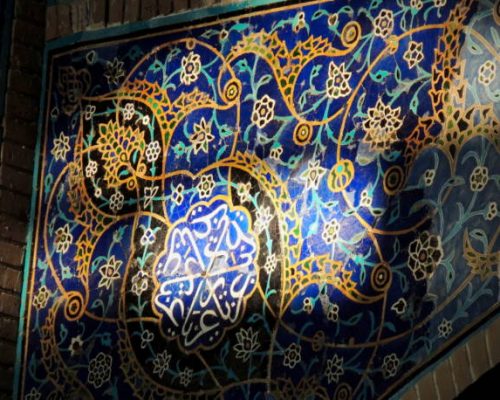 TABRIZ, East Azerbaijan, Iran - Ceramic tilework decorations of Islamic art including floral patterns and Islamic calligraphy, lit up by sunlight, in a corner of the landmark Blue Mosque of Tabriz.